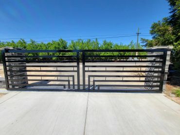 Modern black metal driveway gate with geometric design.