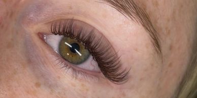 Close-up of an eye with long, curled eyelashes and green iris.