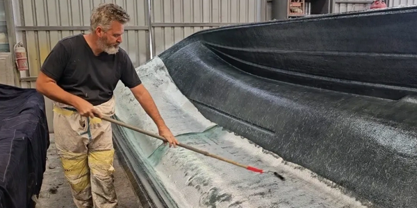 Owner and Shipwright Nigel Johnson laying fiberglass over an Oceanwhaler hull