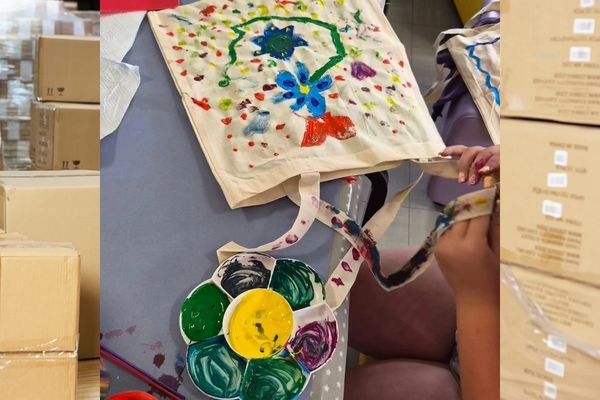 Person painting on a cloth bag with colorful flowers.