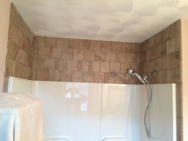 Newly tiled shower wall with installed showerhead.