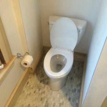 White toilet with open lid in a small bathroom corner.
