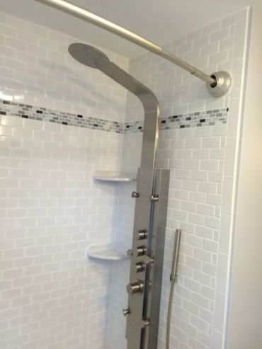 Modern shower panel with overhead and hand shower in tiled bathroom.