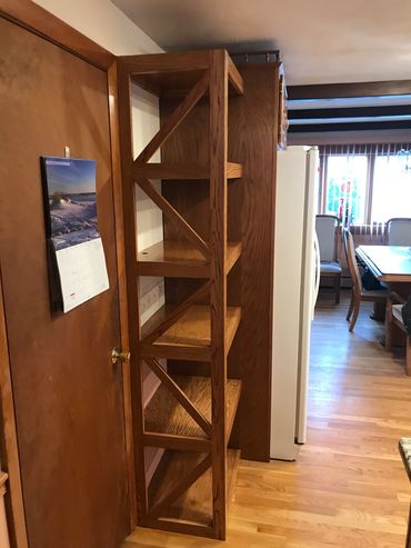 Tall wooden shelving unit in a kitchen corner.