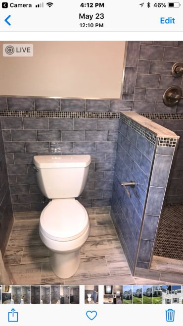 White toilet in a blue tiled bathroom corner.