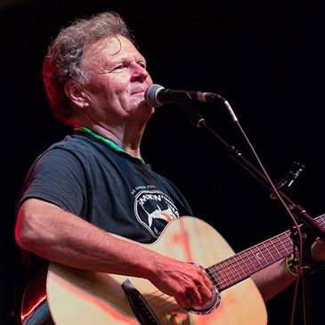 Man playing acoustic guitar and singing on stage.