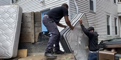 Two men loading mattresses into a truck.