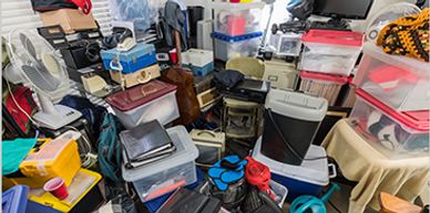 Cluttered room filled with stacked boxes and household items.