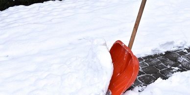 Red snow shovel clearing snow off a pathway.