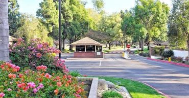 Entrance gate with guardhouse surrounded by colorful flowers and greenery.