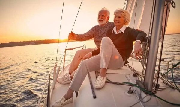 Elderly couple enjoying a serene sunset sail on a boat.