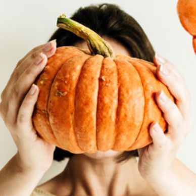 Person holding a pumpkin in front of their face.