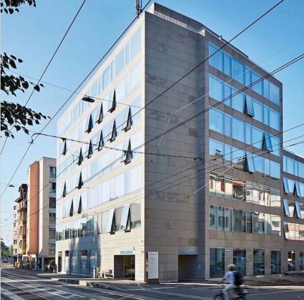 Modern office building with reflective glass windows and unique triangular awnings.