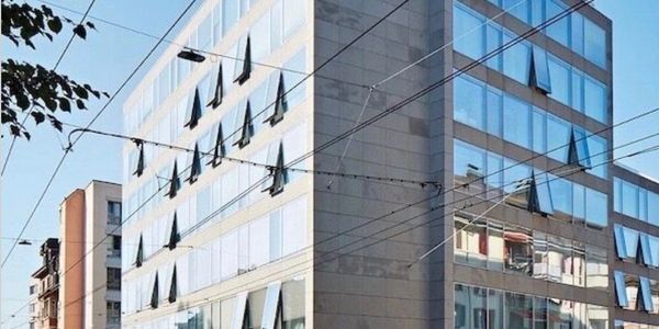 Modern office building with reflective glass windows and unique triangular awnings.