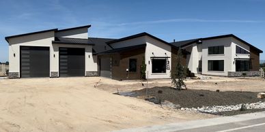 Modern luxury home with white stucco, and angled roof lines with lower accent stone.