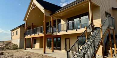 Two-story back patio and deck with large wood beams and iron railings