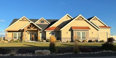 Exterior of craftman-style luxury home with tan paint brown modern stone and copper roof awnings
