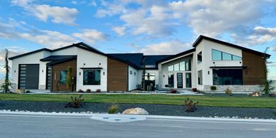 Exterior architectural modern luxury home white stucco large dark wood accents stone water feature