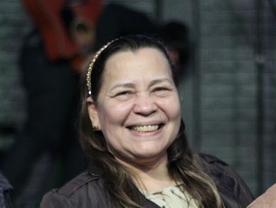 A woman smiling warmly with a background of blurred people.