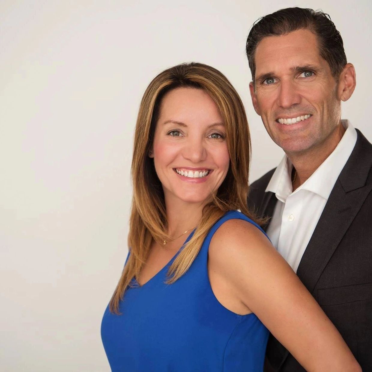 Smiling couple posing together against a plain background.