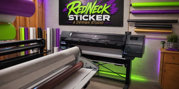 Sticker design studio with printing machines and colorful rolls.
