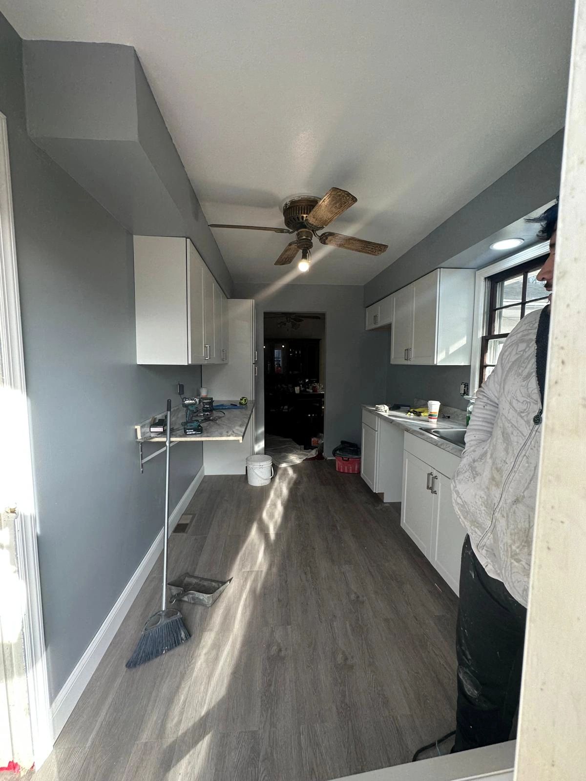 A narrow room with cabinets, tools, and a broom on the floor.