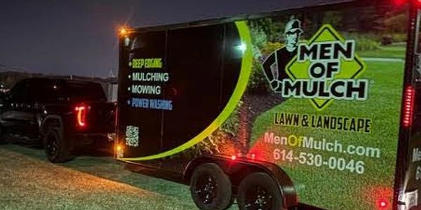 Trailer advertising Men of Mulch lawn and landscape services at night.
