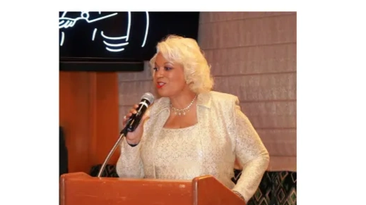 Woman speaking at a podium with a microphone in hand.