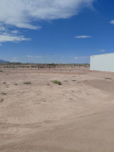 A barren desert landscape with a clear blue sky and a white storage container.