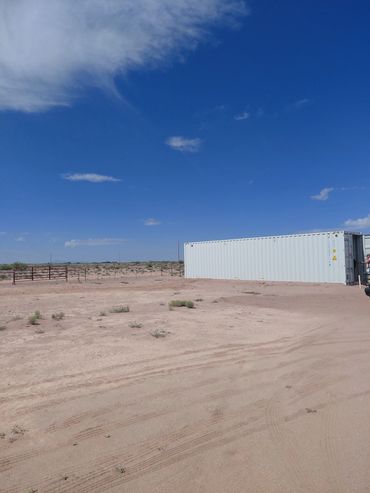 White container in a vast desert landscape under a clear blue sky.