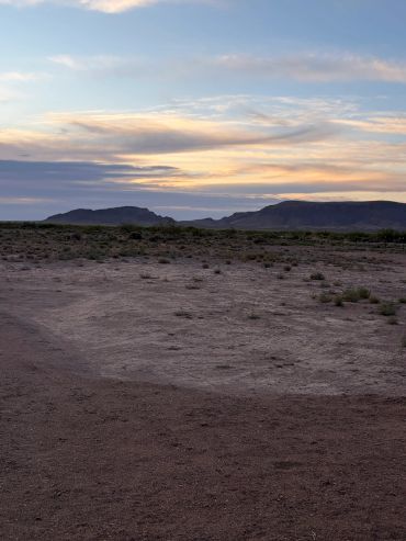 Desert landscape with mountains under a colorful sunset sky.