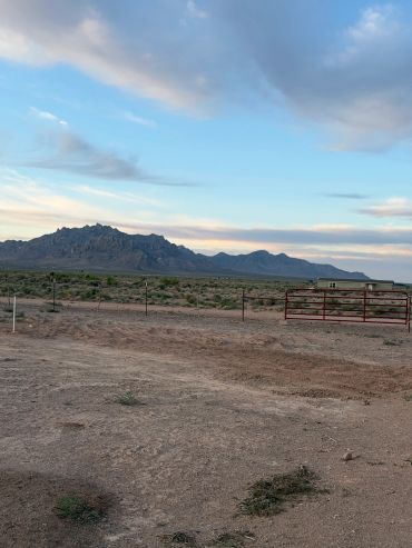 Desert landscape with mountains and a red gate under a cloudy sky.