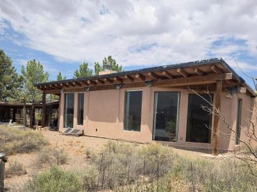 Single-story adobe house in a desert setting.