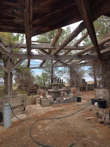 Rustic outdoor structure with plants and pottery in a garden.