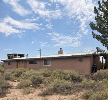 Desert house under a partly cloudy sky.