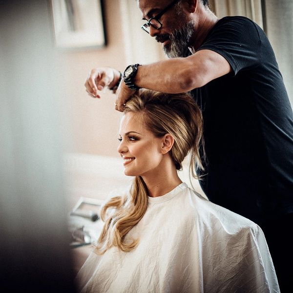 Hairdresser styling woman's hair with a smile.