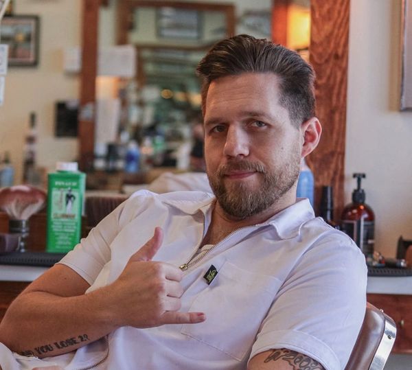 Man in white shirt making a shaka hand gesture indoors.