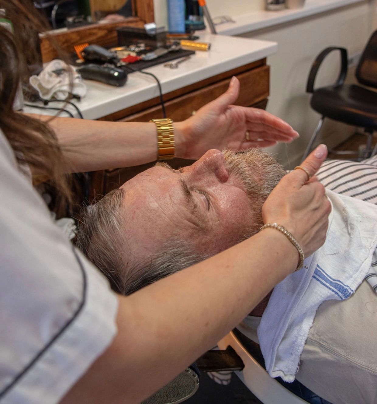 Man receiving a beard grooming treatment at a barber shop.