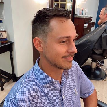 Man with a fresh short haircut sitting in a barbershop chair.