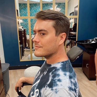 Man with a fresh haircut sitting in a salon chair.