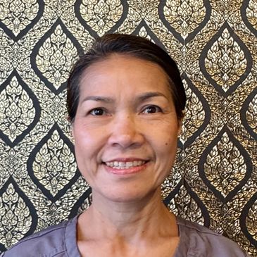 Smiling woman with dark hair against an ornate patterned background.