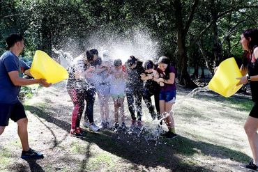 People having a water fight outdoors.