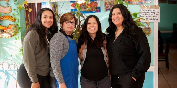 Marta and three of her daughters posing in the restaurant, smiling.