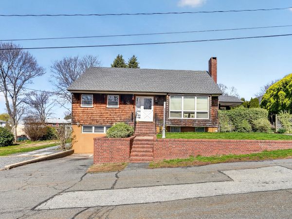 Cozy mid-century house with brick steps and wooden siding under clear blue sky.