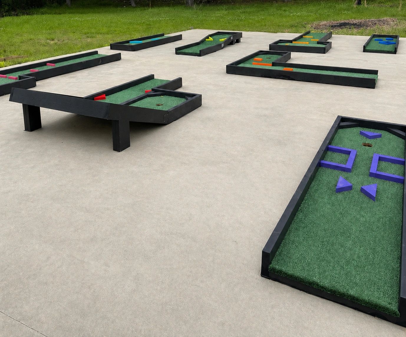 Mini golf course with colorful obstacles on green turf.