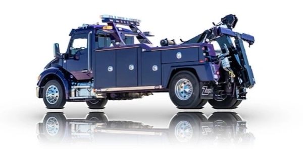 A modern dark blue tow truck with reflective surface below.