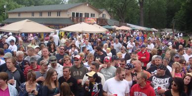 Large crowd gathered outdoors at a festival or event near tents.