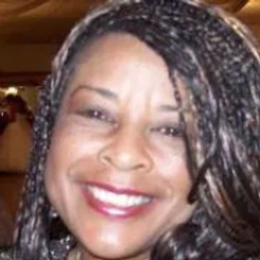 Close-up of a smiling woman with braided hair and red lipstick.