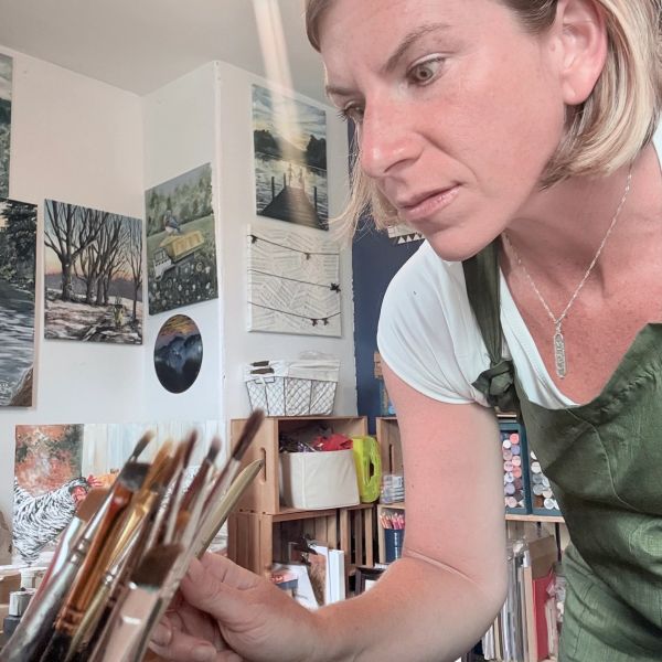 Woman selecting paintbrushes in an art studio.