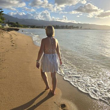 Woman walking along the beach during sunset.